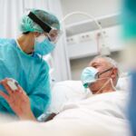 One nurse showing a framed photograph of a relative to a COVID patient.